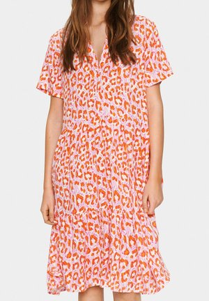 Woman wearing a short-sleeve, knee-length dress with an orange and pink leopard print pattern and a V-neck collar.