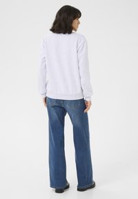 Lichtgrijs sweatshirt met ribbels aan de manchetten en de zoom, gecombineerd met hooggeplaatste wijde blauwe jeans. Schoon ontwerp, geen zichtbare patronen of logo's.