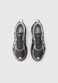 Μαύρα και γκρι αθλητικά παπούτσια με επάνω μέρος από δίχτυ, ανακλαστικές λεπτομέρειες, επενδυμένο γιακά και κορδόνια σε αντίθετο χρώμα. Σχεδιασμένα για άνεση και σταθερότητα.