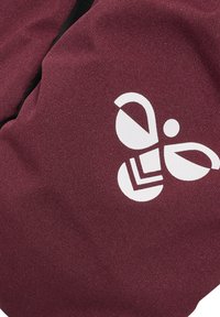 Burgunderfärgad tygpåse med en stor vit abstrakt logotyp. Materialet verkar ha en textur, med framträdande veck och sömmar.