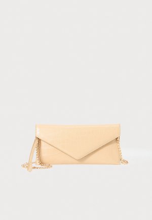 Pochette enveloppe beige à motif crocodile avec chaîne dorée et anse poignet sur fond uni.