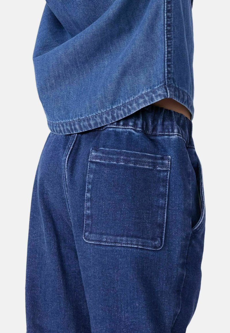 Pantaloni in denim blu scuro con vita elastica, dotati di una tasca posteriore singola e una vestibilità comoda. Il tessuto presenta una leggera trama.