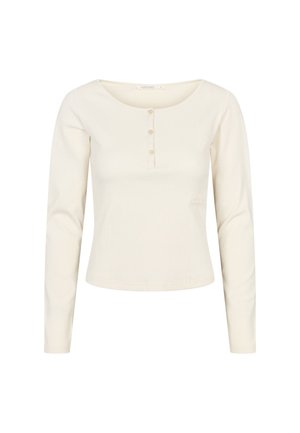 Haut à manches longues crème en tissu côtelé avec un col rond, doté d'une patte de boutonnage et d'un petit logo sur le côté.