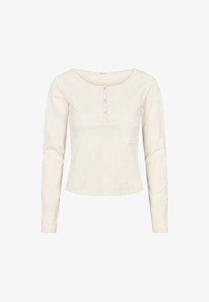 Haut à manches longues crème en tissu côtelé avec un col rond, doté d'une patte de boutonnage et d'un petit logo sur le côté.