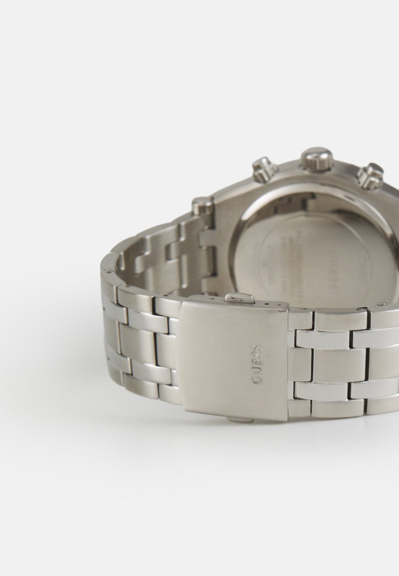 Orologio in acciaio inox con finitura spazzolata, robusto bracciale e fibbia. Presenta più pulsanti sul lato e una cassa rotonda liscia.