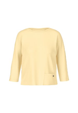 Yellow three-quarter sleeve top made of soft material, featuring a round neckline, a side pocket, and a small decorative metal accent.