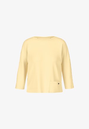 Gelbes Dreiviertelarm-Oberteil aus weichem Material, mit rundem Ausschnitt, einer Seitentasche und einem kleinen dekorativen Metallelement.