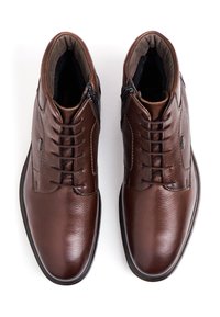 Brown leather ankle boots featuring a smooth finish, textured accents, lace-up front, and side zippers for easy wear.