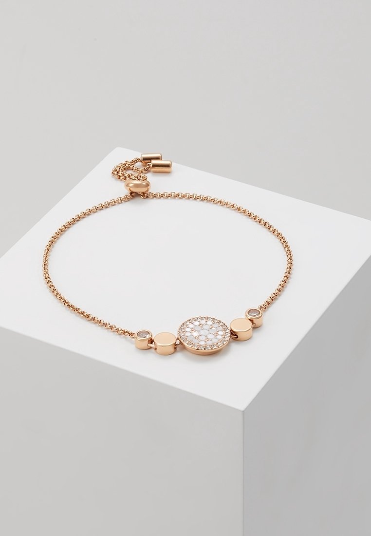 Bracelet délicat en or rose avec chaîne ajustable et charms circulaires, comprenant un charm central serti de cristaux blancs.