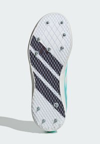 Suola di scarpa con tacchetti featuring un motivo a diamante bianco e nero, dettagli turchesi e borchie metalliche visibili per la presa. Superficie testurizzata in tutto il prodotto.