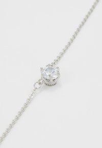 Silversmycke i kedja med en central rund klar kristall i en klorinställning, prydd med små pärl-accenter.