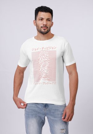 Camiseta blanca con un diseño gráfico de línea roja. Texto en japonés e inglés. Mangas cortas, tejido de algodón suave, corte casual, jeans desgastados de color azul claro.