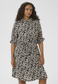 Short-sleeve, button-up dress in beige and navy with a zigzag pattern. Features a tie waist and knee-length cut with pleated sleeves.