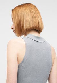 Γκρι αμάνικο τοπ με ριπ υφή, μαλακό γιακά και υφασμάτινη δομή, με εφαρμοστή σχεδίαση και καθαρή γραμμή στο λαιμό.