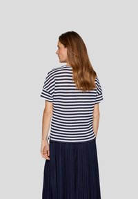 Navy and white striped short-sleeve top with a round neckline and subtle texture, paired with a pleated navy skirt.