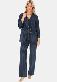 Granatowy garnitur w paski z podwójnym zapięciem, posiadający złote guziki, luźne spodnie i teksturowany materiał.