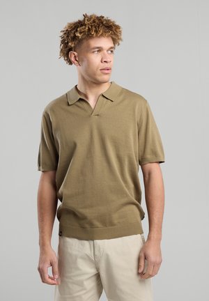 Polo a maniche corte in tessuto a maglia verde oliva con scollatura a V, orlo a costine e vestibilità comoda. Presenta una superficie leggermente texturizzata.