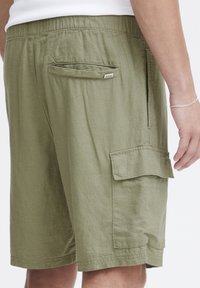 Shorts cargo kaki en tissu texturé, avec une poche arrière, une poche cargo sur le côté et une taille élastique pour plus de confort.
