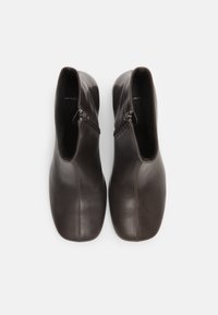 Brown leather ankle boots with side zippers, rounded toe, smooth texture, and seam detailing, viewed from above.