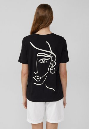 T-shirt en coton noir avec un dessin de visage en ligne blanche au dos. Le design comprend un accent d'oreille. Manches courtes et col rond.