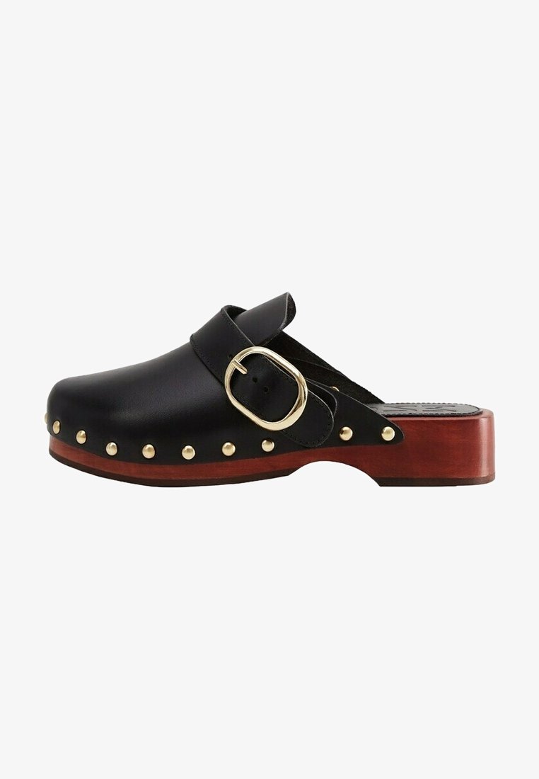 Sabot en cuir noir avec une large boucle dorée et des clous dorés le long de la semelle, avec un talon en bois marron et un design ouvert à l'arrière.