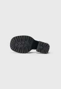 Talpa de pantof din cauciuc negru, cu model adânc și fixat floral. Suprafață texturată pentru aderență și o zonă a călcâiului întărită.