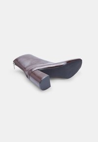 Brown leather ankle boot with a smooth texture, side zipper, and a chunky square heel. The sole is black with a slight grip pattern.