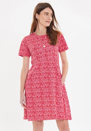 Rotes Kleid mit kurzen Ärmeln und einem zebraähnlichen Muster. Der Stoff ist glatt, mit einem taillierten Oberteil, einem ausladenden Rock und seitlichen Taschen.