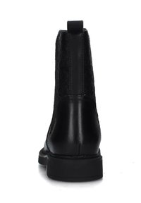 Stivaletto nero con retro testurizzato, tomaia in pelle liscia e suola in gomma bassa. Dotato di linguetta sul retro per una facile calzata.