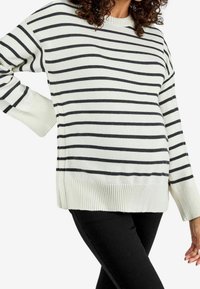Maglione a righe bianche e nere con polsini e orlo a costine. Maniche lunghe e vestibilità comoda, realizzato in un morbido materiale a maglia.