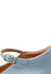 Chaussure en cuir verni bleu clair avec doublure intérieure marron et une bride à boucle ovale argentée.