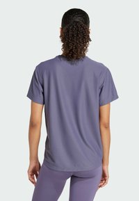 Lila kurzärmliges Sportshirt aus strukturiertem Stoff, mit Rundhalsausschnitt und lockerer Passform, kombiniert mit passenden Leggings.