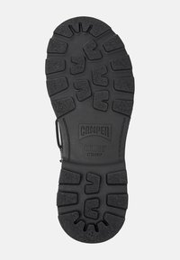 Black rubber shoe sole with thick tread pattern, featuring the "Camper Bridge Xtragrip" logo and size 42 marking.