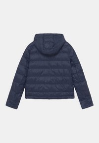 Granatowa pikowana kurtka z kapturem, o dopasowanym kroju. Gładka tekstura materiału z lekkością w wyglądzie.