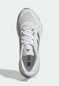 Weißer Sportschuh mit einem Obermaterial aus Mesh, mit strukturiertem Design, Schnürverschluss und dezenten Akzentstreifen an den Seiten. Durchsichtige Gummisohle.