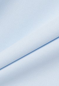 Tela azul claro doblada en diagonal, mostrando una textura suave y tejida de forma apretada con sutiles líneas diagonales.