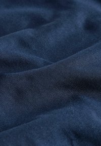 Textil de culoare albastru marin cu o textură netedă, având o ușoară elasticitate, un model de țesătură vizibil și o strălucire ușoară datorată luminii.