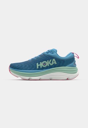Ténis de corrida azuis com um exterior texturizado, apresentando o logo verde "HOKA", entressola verde-clara, acentos na sola rosa e um design de calcanhar proeminente.