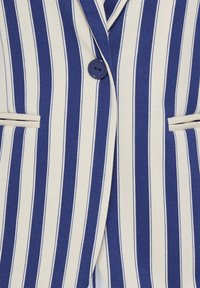 Blazer à rayures verticales bleu marine et blanc avec un seul bouton bleu marine et deux poches horizontales passepoilées à l'avant.