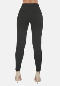 Czarne legginsy z wysokim pasem, dopasowane, z dwiema kieszeniami z tyłu. Gładki, elastyczny materiał sięga do kostek.