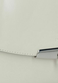 Witte leren handtas met een glad oppervlak, subtiele stiksels en een zilverkleurige sluiting. Elegante, minimalistische ontwerp met strakke lijnen.