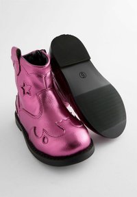 Metallisch pinke Knöchelstiefel mit Sternelementen und schwarzer Gummisohle. Sie verfügen über eine glatte Textur und dekorative Ausschnitte im Obermaterial.
