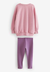Rosa sweatshirt med långa ärmar och ribbade mudd, kombinerad med lila leggings, båda tillverkade av mjuk bomull.