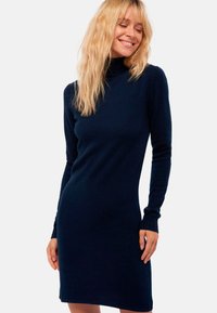 Robe en tricot bleu marine à manches longues avec col bénitier. Présente des poignets côtelés et une silhouette ajustée, fabriquée dans un tissu doux et texturé.