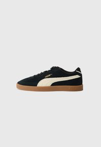 Black suede sneakers with cream suede stripes, featuring a gum rubber sole and gold "PUMA" branding on the side and heel.