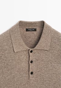 Polo a maglia marrone con colletto a costine, tre bottoni neri e una texture morbida. L'etichetta indica "Massimo Dutti, Made in China."