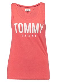 Koralfärgad ärmlös linne i mjuk bomull, med V-ringning, rak fåll och vit text framtill som säger "TOMMY JEANS."