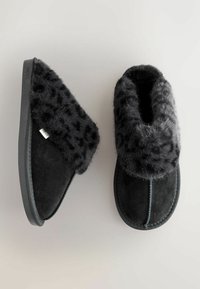 Pantofole nere con un morbido risvolto in pelliccia leopardata e un'esterno liscio di un nero più scuro. Suola in gomma per una migliore aderenza. Cuciture visibili.