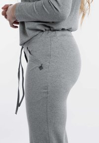 Grijze katoenen sweatpants met een trekkoord in de taille, zijzakken en een klein logodetail op de zak. Zachte textuur en slank pasvormontwerp.