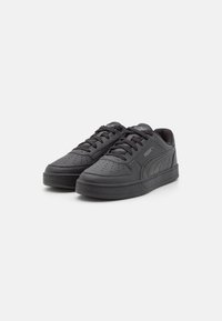 Schwarze Sportschuhe aus synthetischem Leder, mit Schnürdesign, perforierter Zehenpartie für Atmungsaktivität und auffälligem Markenlogo an der Seite.